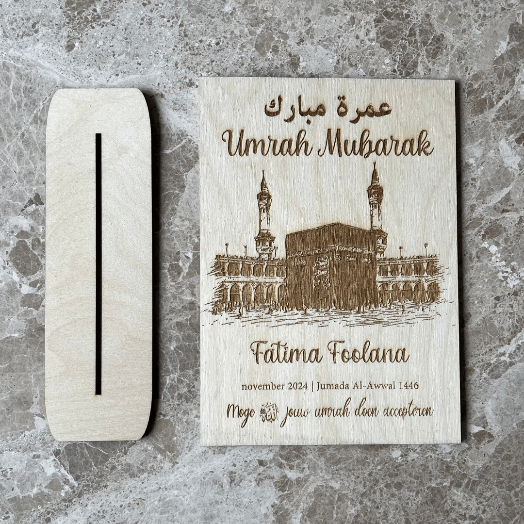 Houten bord met Umrah en Hajj mubarak erop.